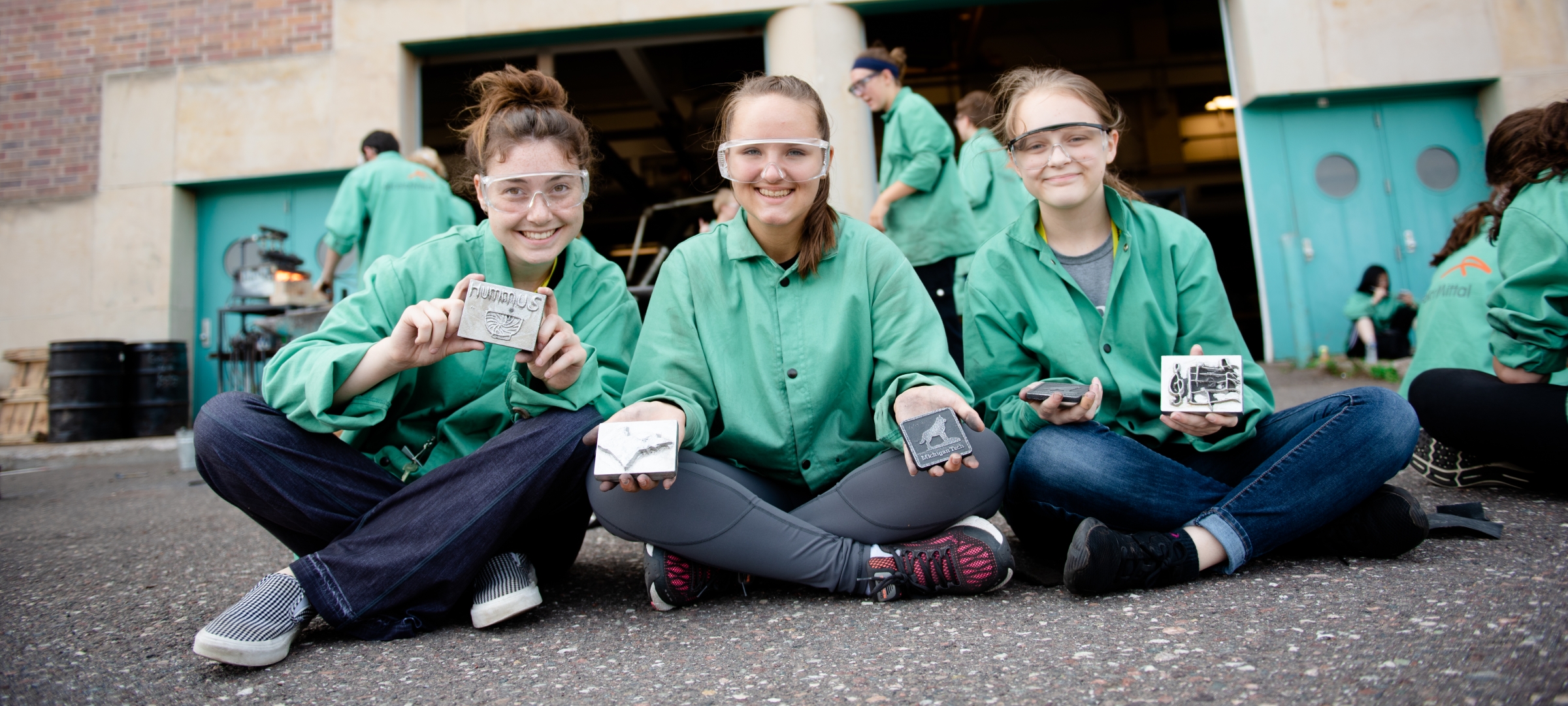 Three students displaying their metal casting from Women in Engineering