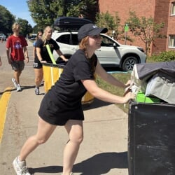Two Thompson Scholars (one with red hair and hat) are moving students into residence halls with carts.