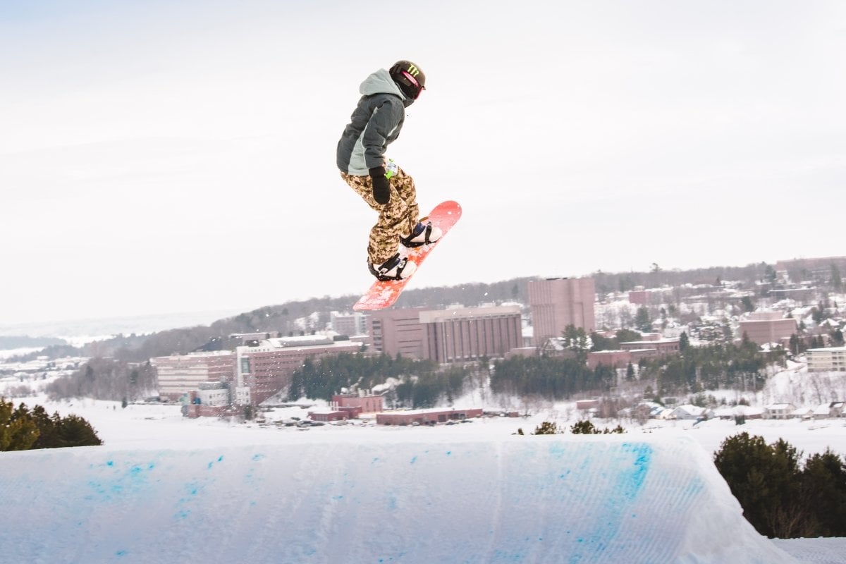 Snowboarder in the air with Michigan Tech in the background.