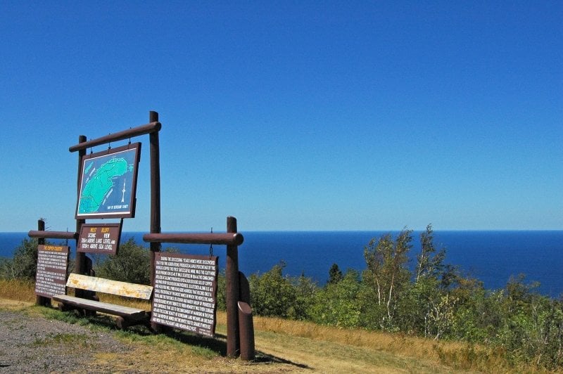 Signs about Copper Harbor overlooking trees and water.