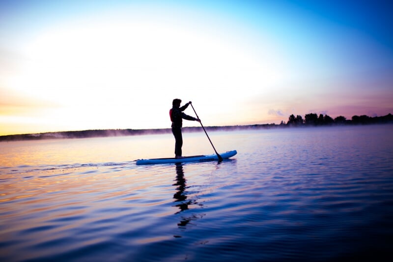 Person paddle boarding in the sunset.