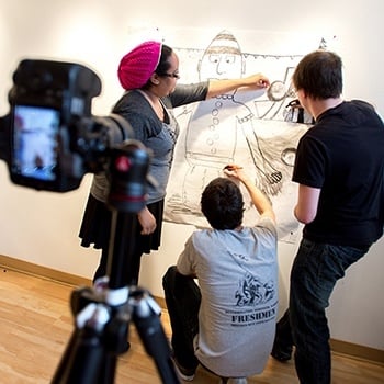 Students drawing art on a wall.