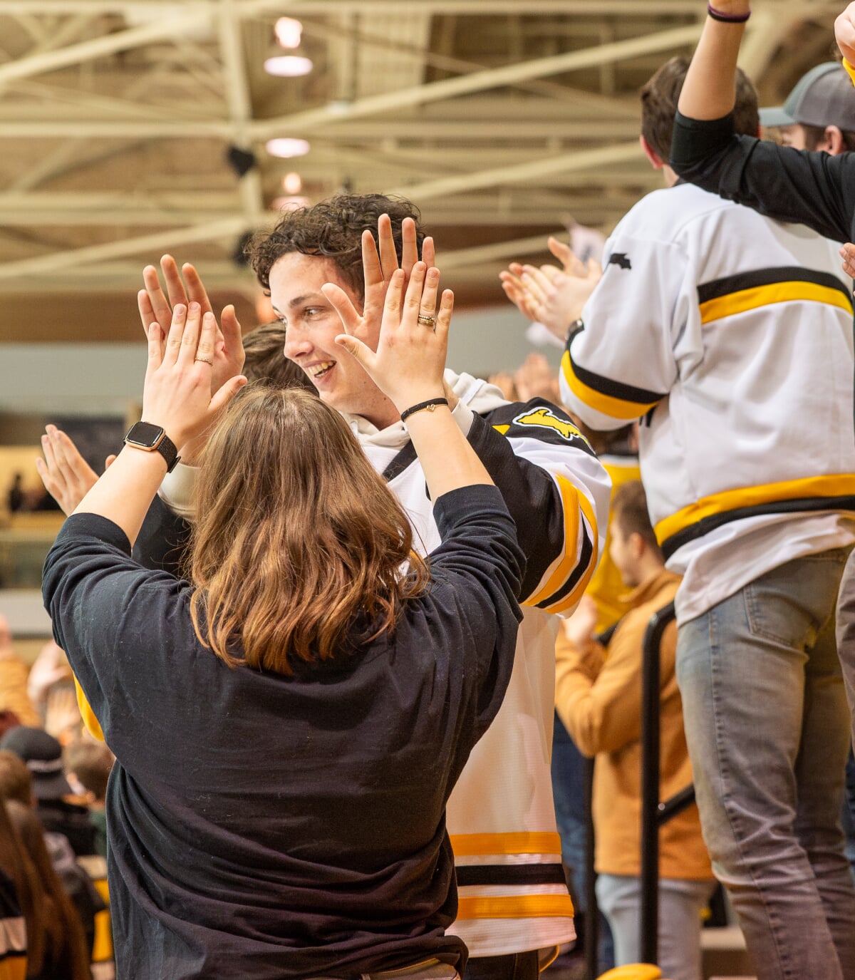 Students high-fiving in the stands at a hockey game.