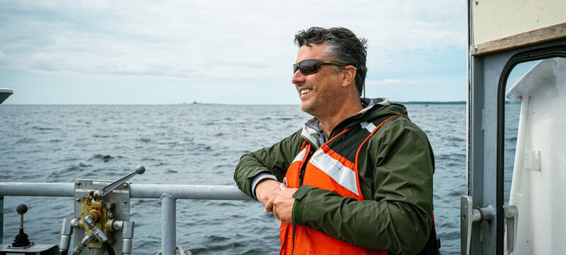 Person wearing a life jacket on a boat on the water.