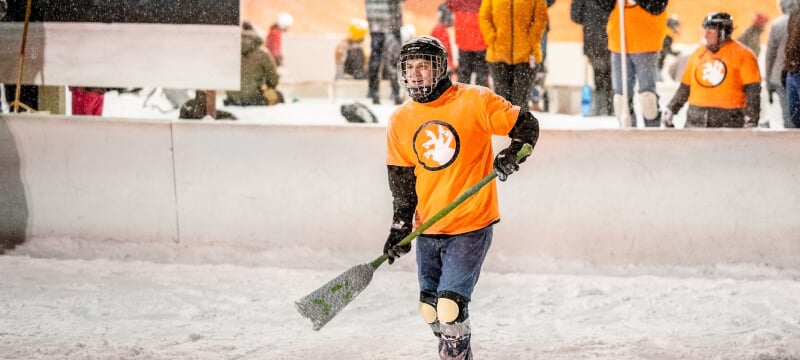 Student in protective gear playing broomball.