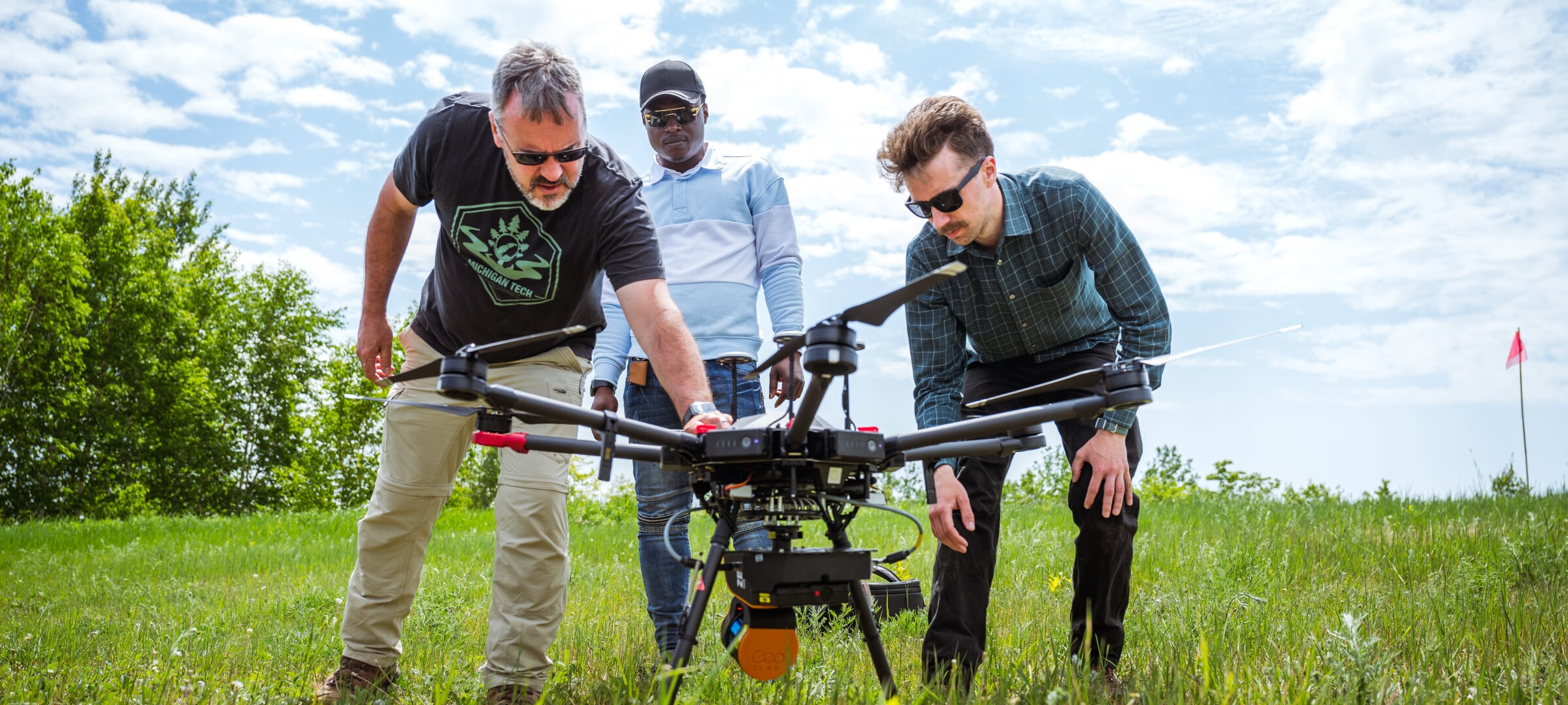 Researchers setting up a drone in the grass.