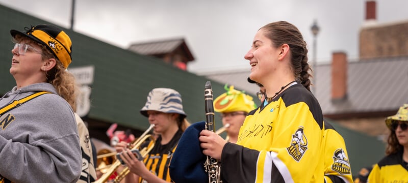 Pep band students playing instruments in a parade.