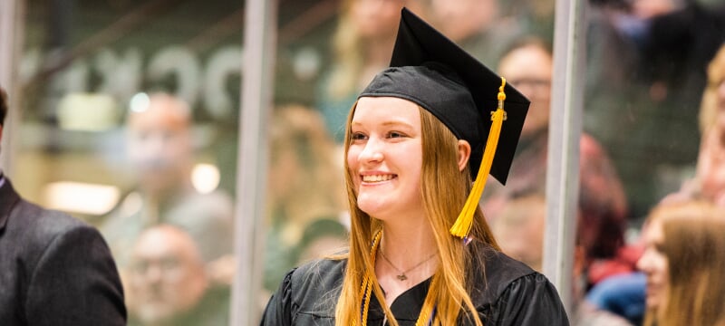 Happy student wearing a cap and gown at commencement.