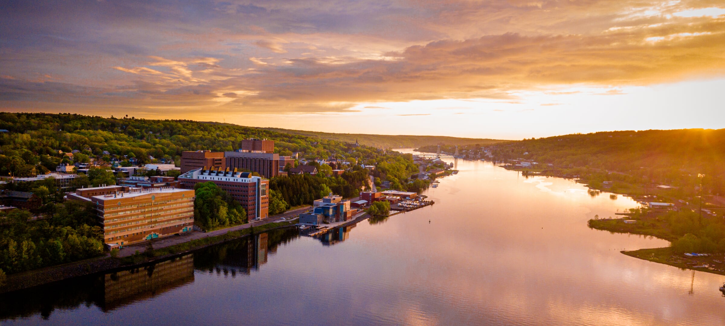 Aerial view of a sunset over campus and the Keweenaw Waterway.
