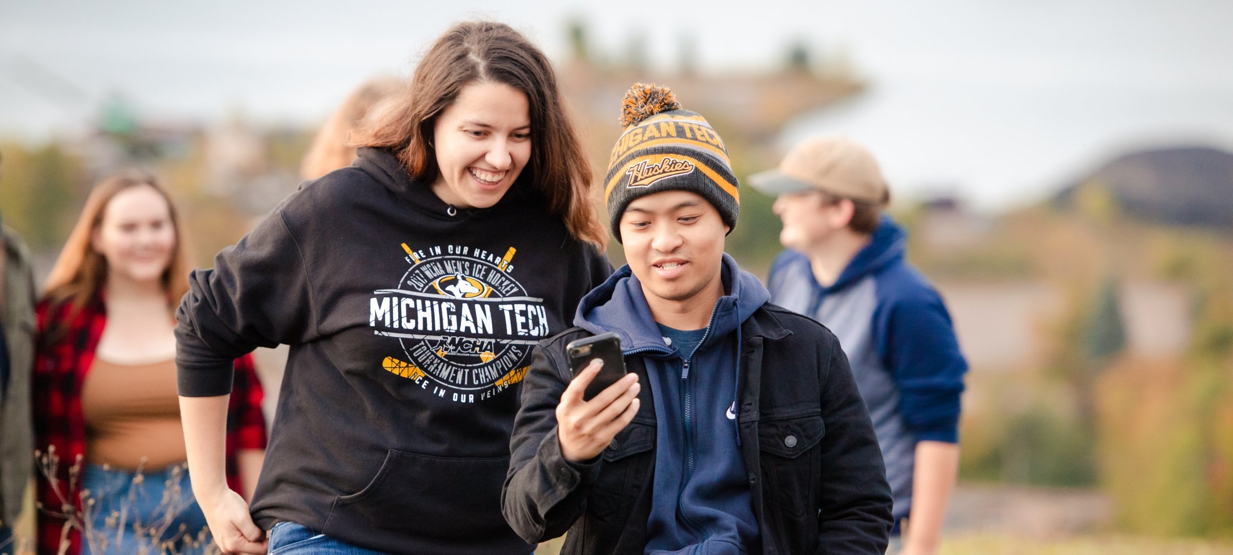 Two students walking one looking at the other's phone