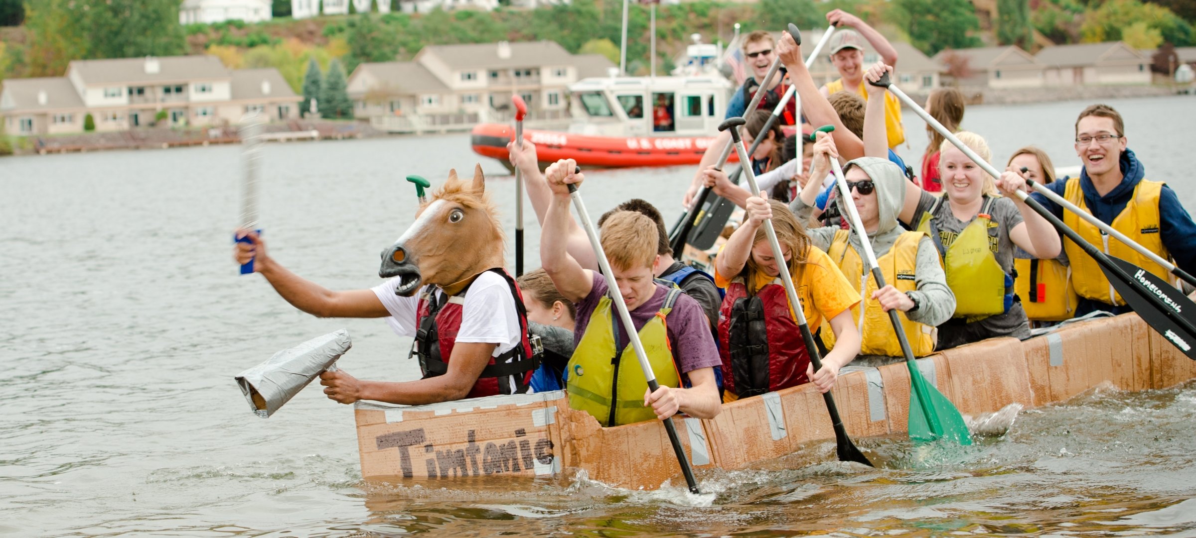 Students in a cardboard boat on the water.