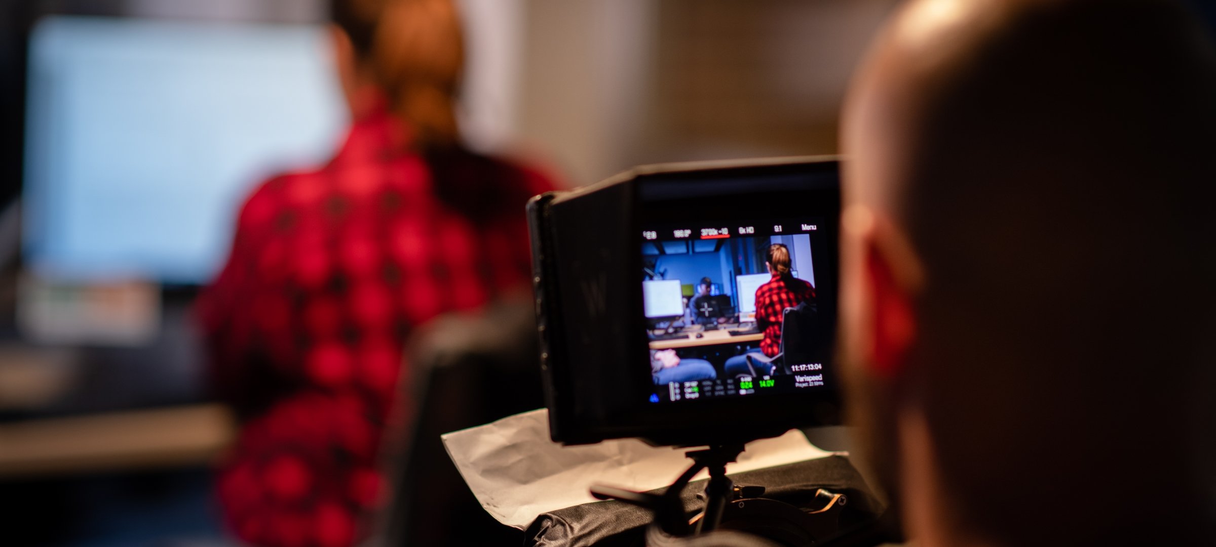 Videographer filming someone at a computer.