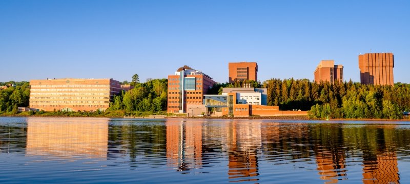 A summer view of Michigan Tech campus from across the waterway.