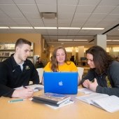 Students at a table with a laptop.