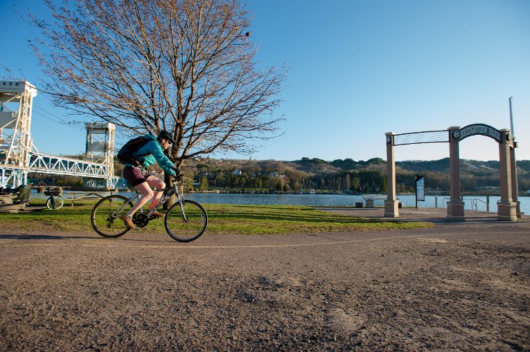Person biking on the waterfront near the bridge.