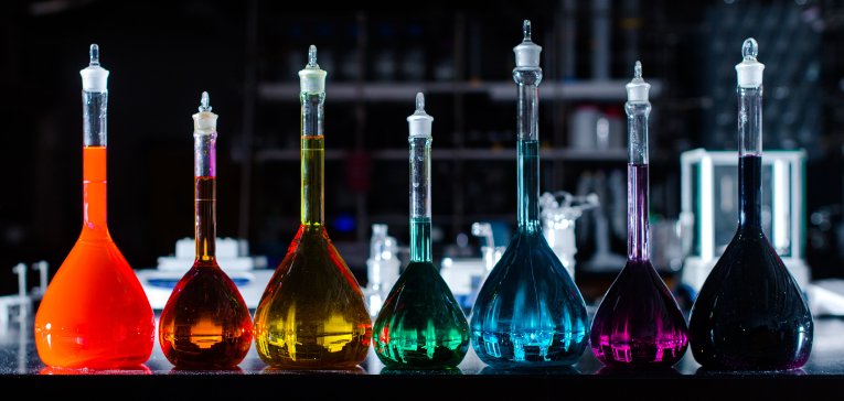 Beakers of colored liquids on a table.