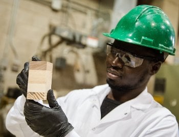 Munkaila Musah holds up a block of cross-laminated timber.