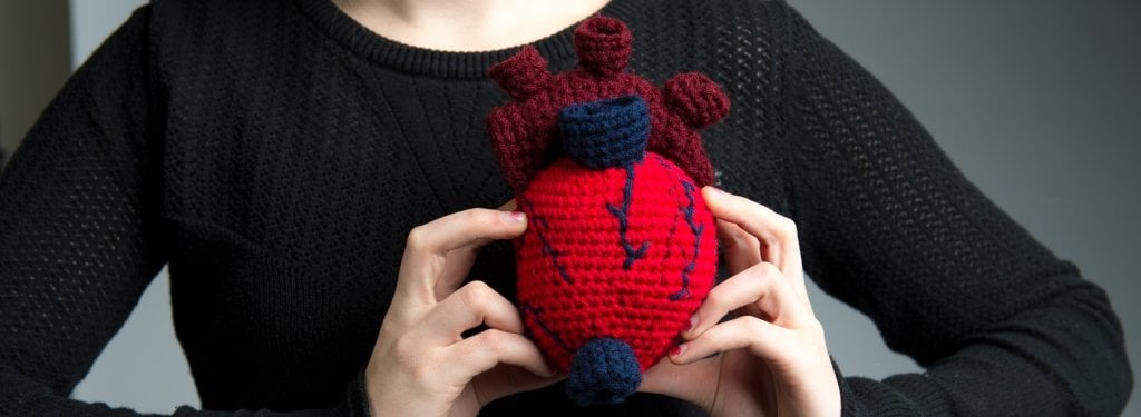 close-up of a young woman holding a crocheted heart