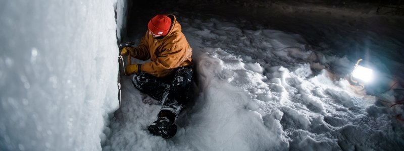 A student chisels the side of a snow statue.