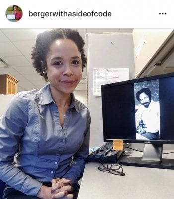 a woman in front of a desktop computer with the image of a man on it