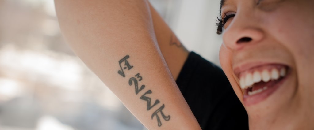 Closeup of smiling young woman with a math symbol tattoo