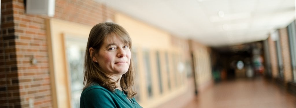 Kelly Kamm of kinesiology stands in an empty hallway 