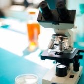 A microscope sits on a counter top beside a petri dish with yeast in it.