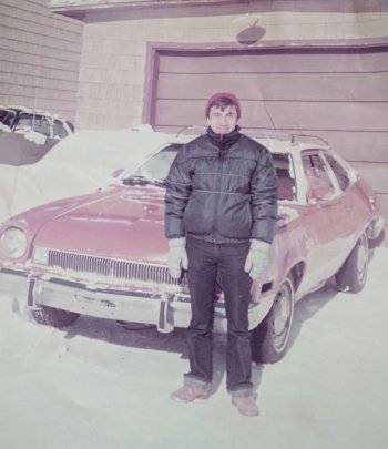 Youthful Orhan standing beside a car.