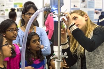 a family stands around a student and equipment at a fair