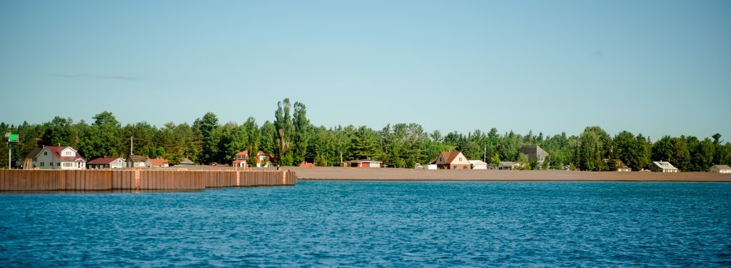 break water at Grand Traverse with stamp sands and town along the forest edge