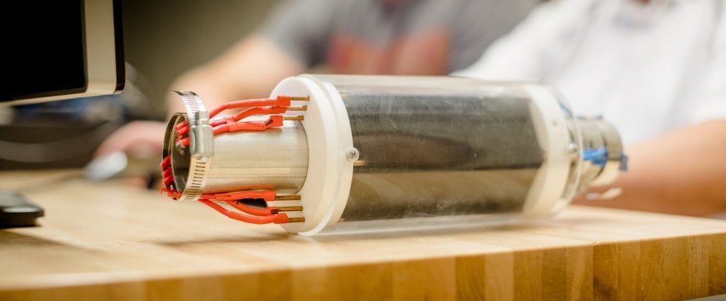 a clear tube filled with thin lines of black sits on a table