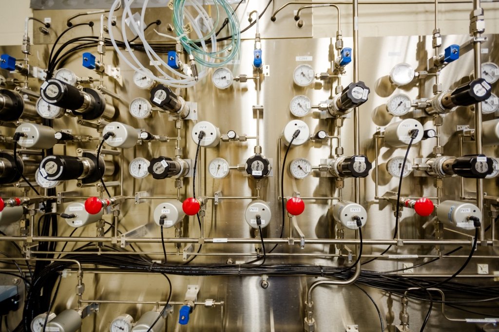 A chrome wall covered with valves, regulators, cords, wires and tubing. 