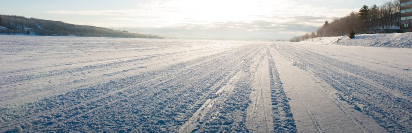 snowmobile tracks in snow under a bright sun