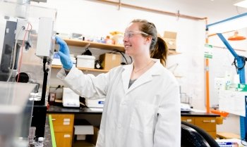 woman in white lab coat adjusting a device