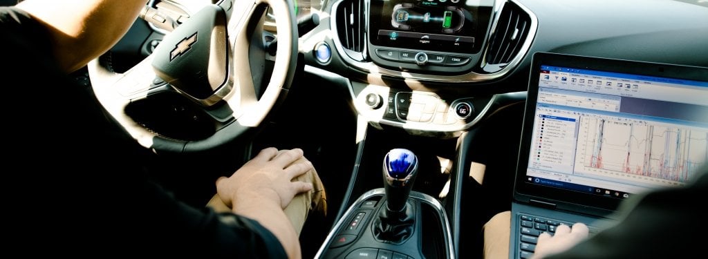 dashboard of an electric vehicle with laptop visible in passenger seat