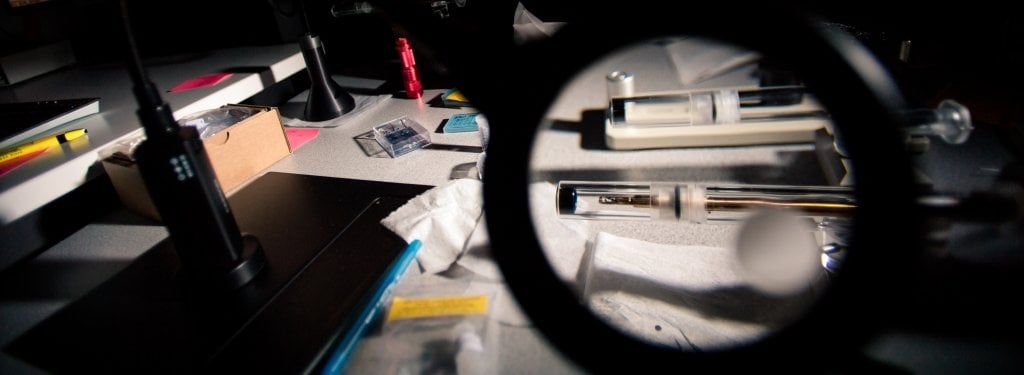 Tools used to adjust samples before they are analyzed in the scanning transmission electron microscope magnified by a magnifying glass.