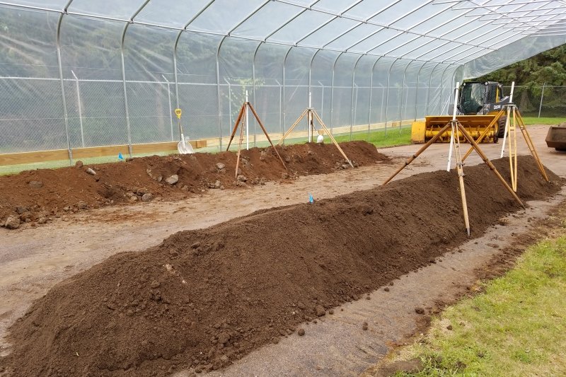 Piles of biosolids dry under a high-wall high tunnel.