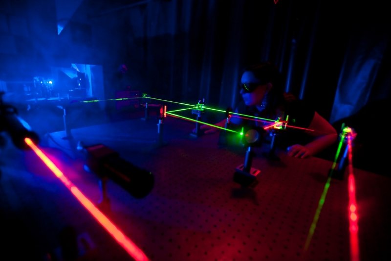 green and blue lasers, woman leaning over table with safety glasses on