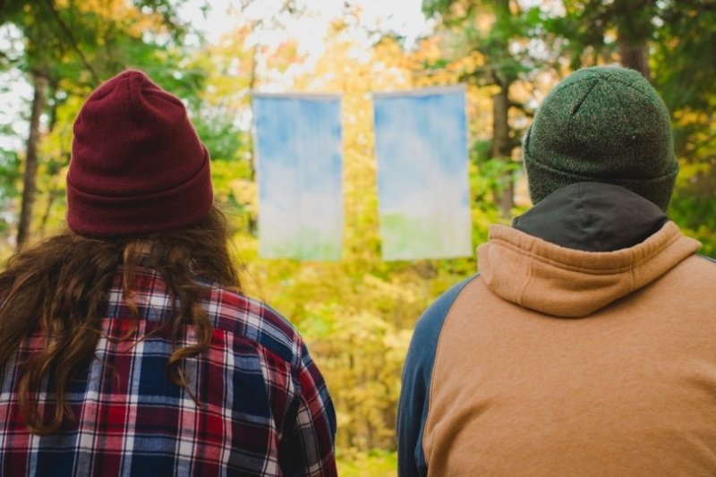 two people facing away looking at cloth banner in tree