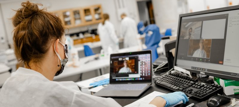 person sitting in front of laptop with laboratory class background