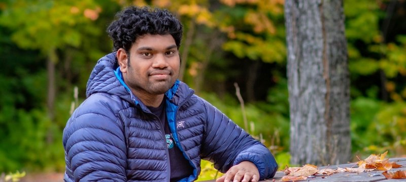 A man sits at a picnic table with autumn colors behind and in front of him on Michigan's Kweenaw Peninsula.