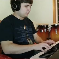 A young man who leads a VGM band plays keyboards with bongos behind him