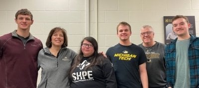 The line-up of winners in the Michigan Tech memorial scholarship cookie cutter contest stand in the shop together.