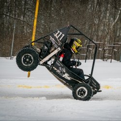 Michigan Tech's baja vehicle with its rear wheels up in a stoppie on a snow and ice track in a winter invitational