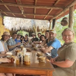 Students sit at a table in the Yucatan outside at a honey-tasting at a bee farm.