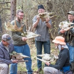 Isle Royale Moosewatch volunteers hold moose skulls and other bones they located while participating in citizen research.