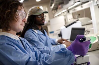 Two graduate students work with equipment in the Genomic Sequencing Lab at Michigan Tech.