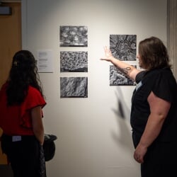 Terri Jo Frew and an exhibit attendee admire a collection of six black and white microscopic images on display in the Rozsa Art Galleries.