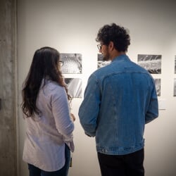 Two exhibit attendees stand in front of a wall of black and white microscopic images on display in the Roza Art Galleries.