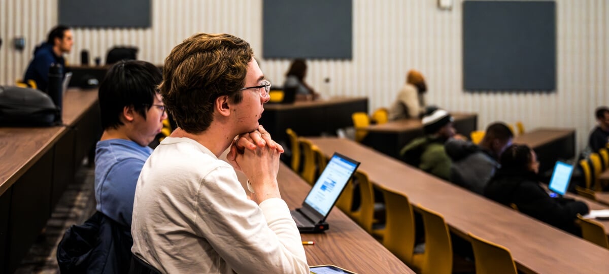 Michigan Tech data science students practice their craft in and out of the classroom, learning to clean data and train the learning models that shape modern decision making across industries. Students in a tiered seating lecture hall.